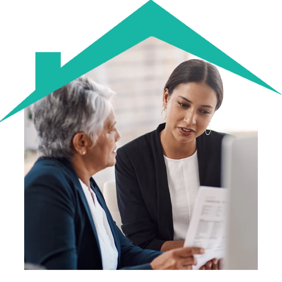 Two women discussing documents under a house roof.