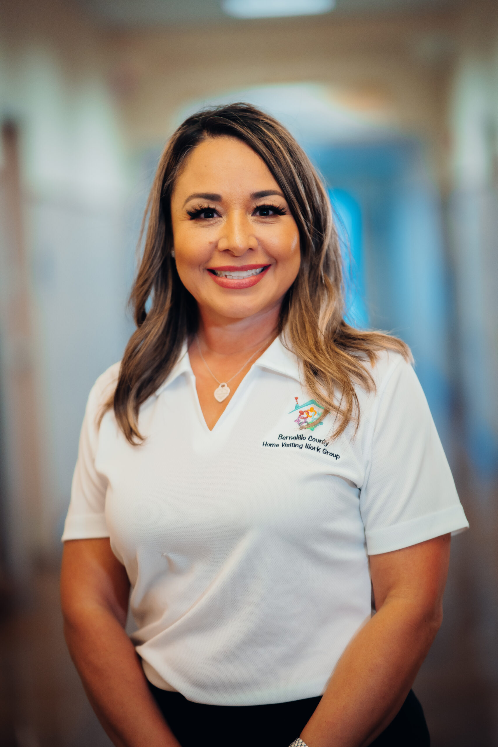 Woman smiling in white shirt with logo.