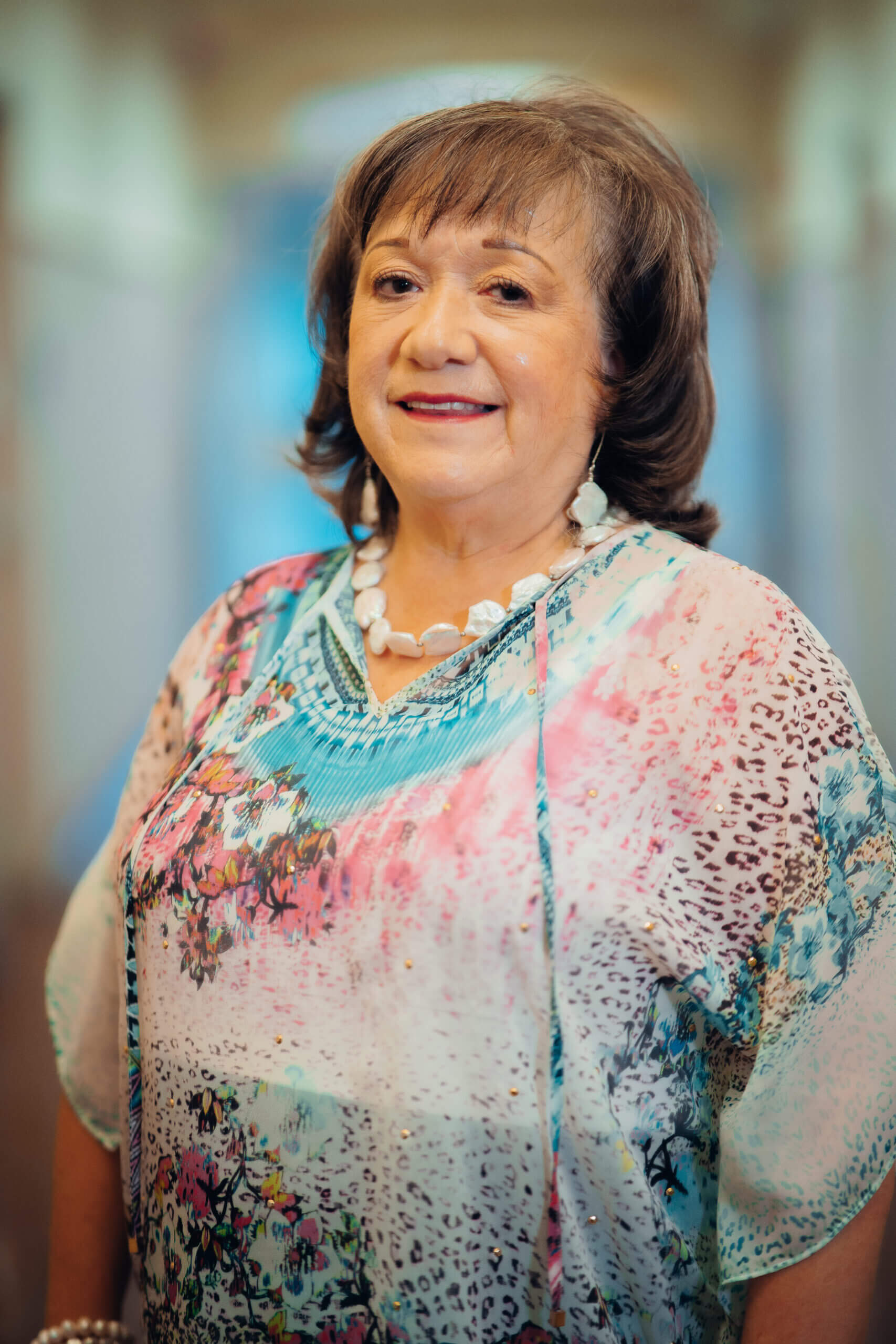 Smiling woman wearing floral print top.