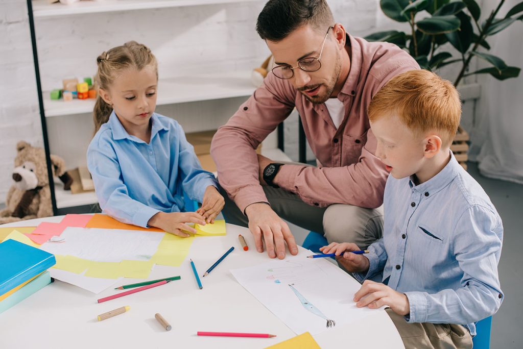 Children and teacher drawing at a table.