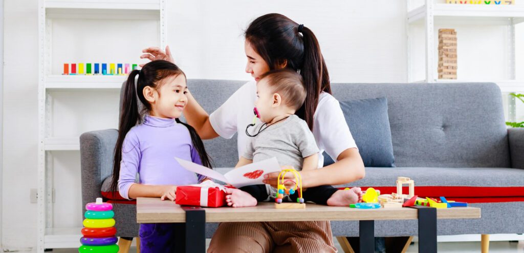 Mother reading card to daughter and baby